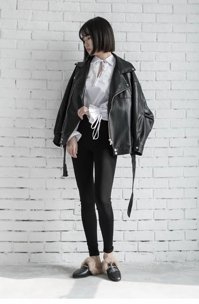 Woman wearing black faux leather motorcycle jacket with belt