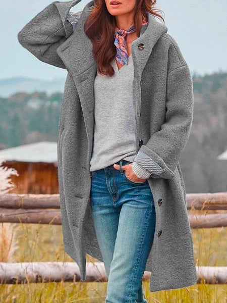 Woman wearing long hooded button coat with side pockets