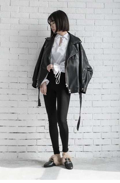 Woman wearing black faux leather motorcycle jacket with belt