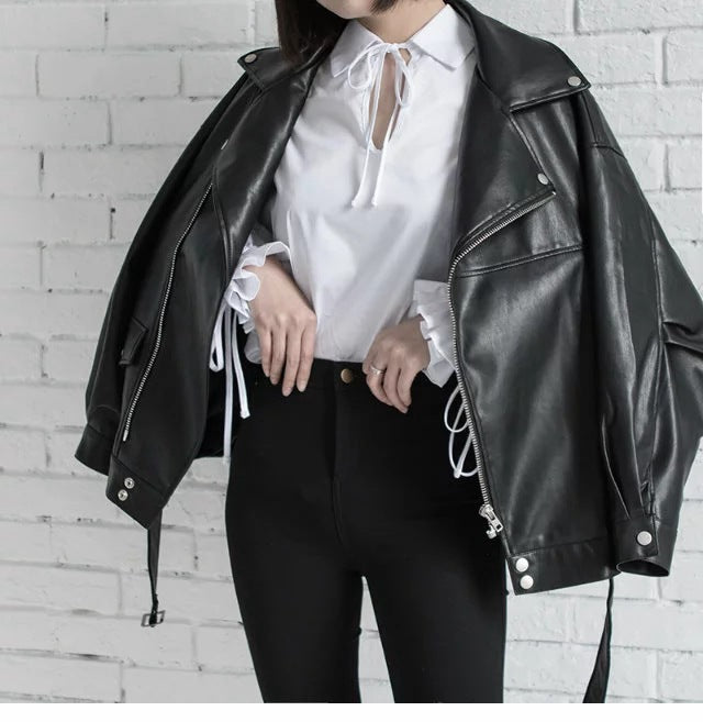 Woman wearing black faux leather motorcycle jacket with belt